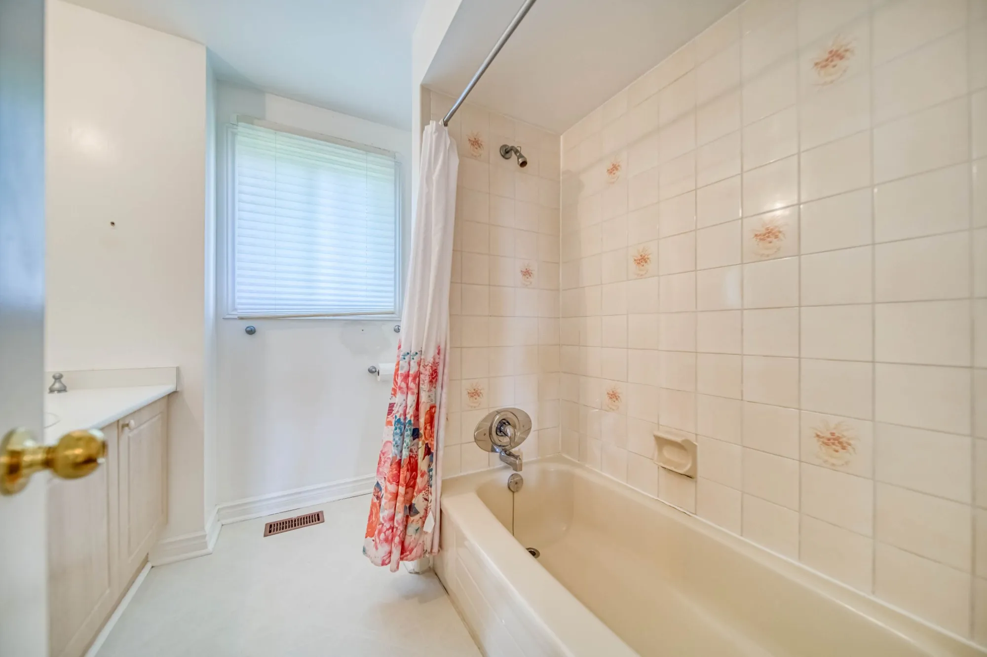 The bathroom before: a beige tub with floral tile.