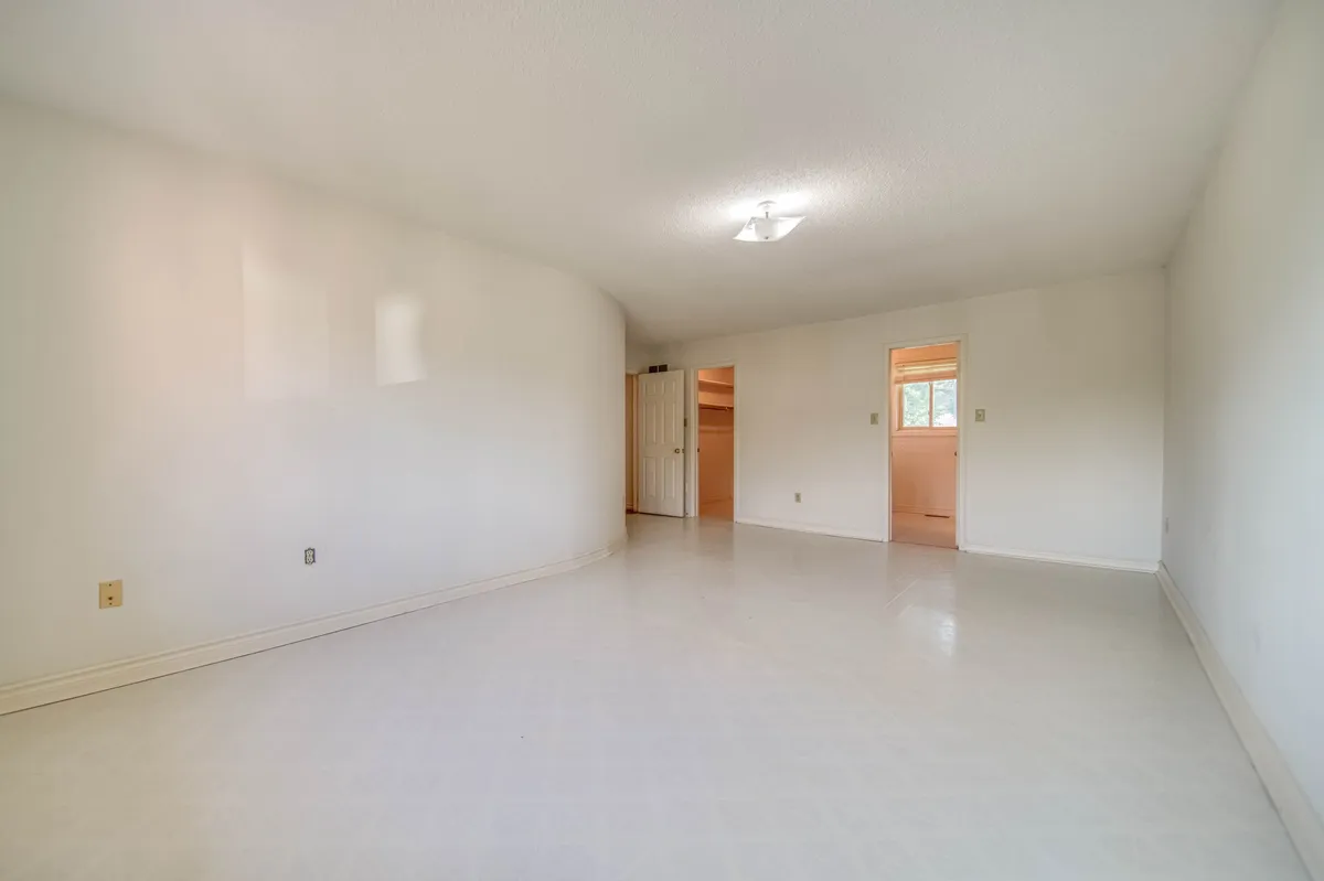 The primary bedroom before: an empty room with a vinyl floor.