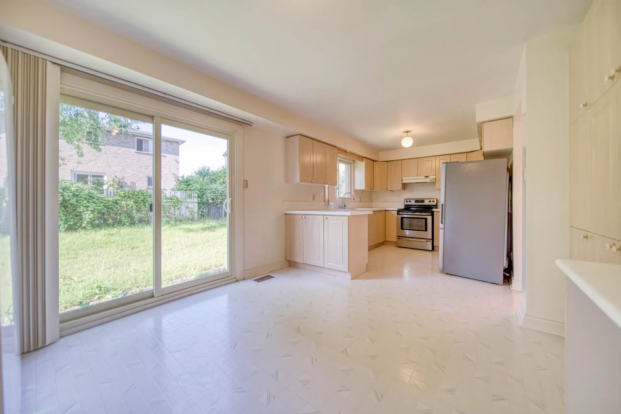 The kitchen before: maple cabinets, a tiled floor and a sliding door to the yard.