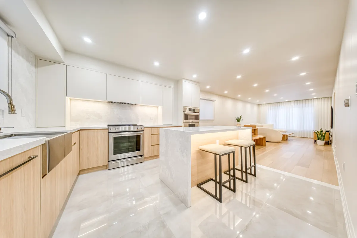 The finished kitchen: a stone waterfall island with stools, oak lowers and white uppers.