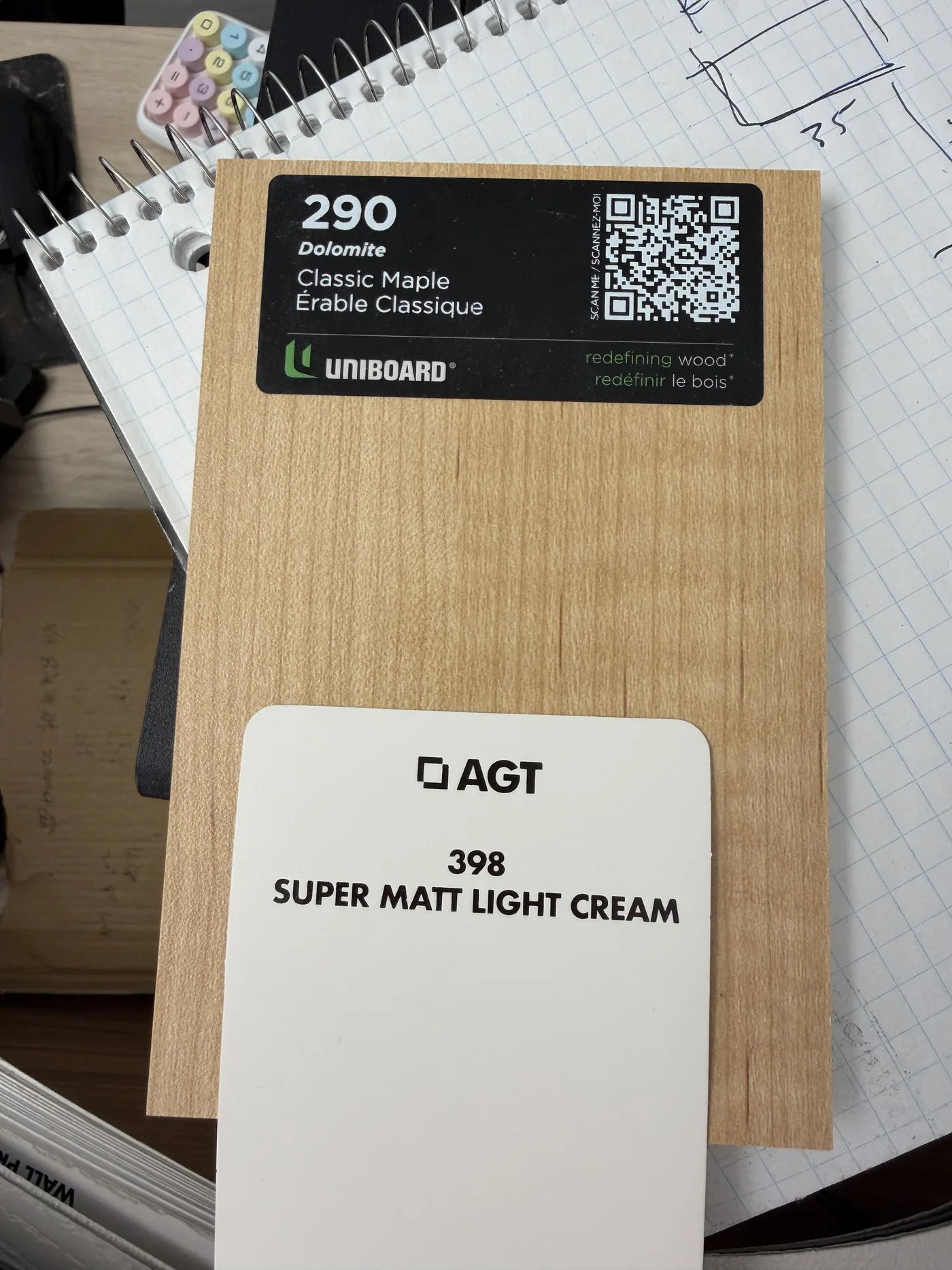 An oak veneer sample beside a cream cabinet colour card.