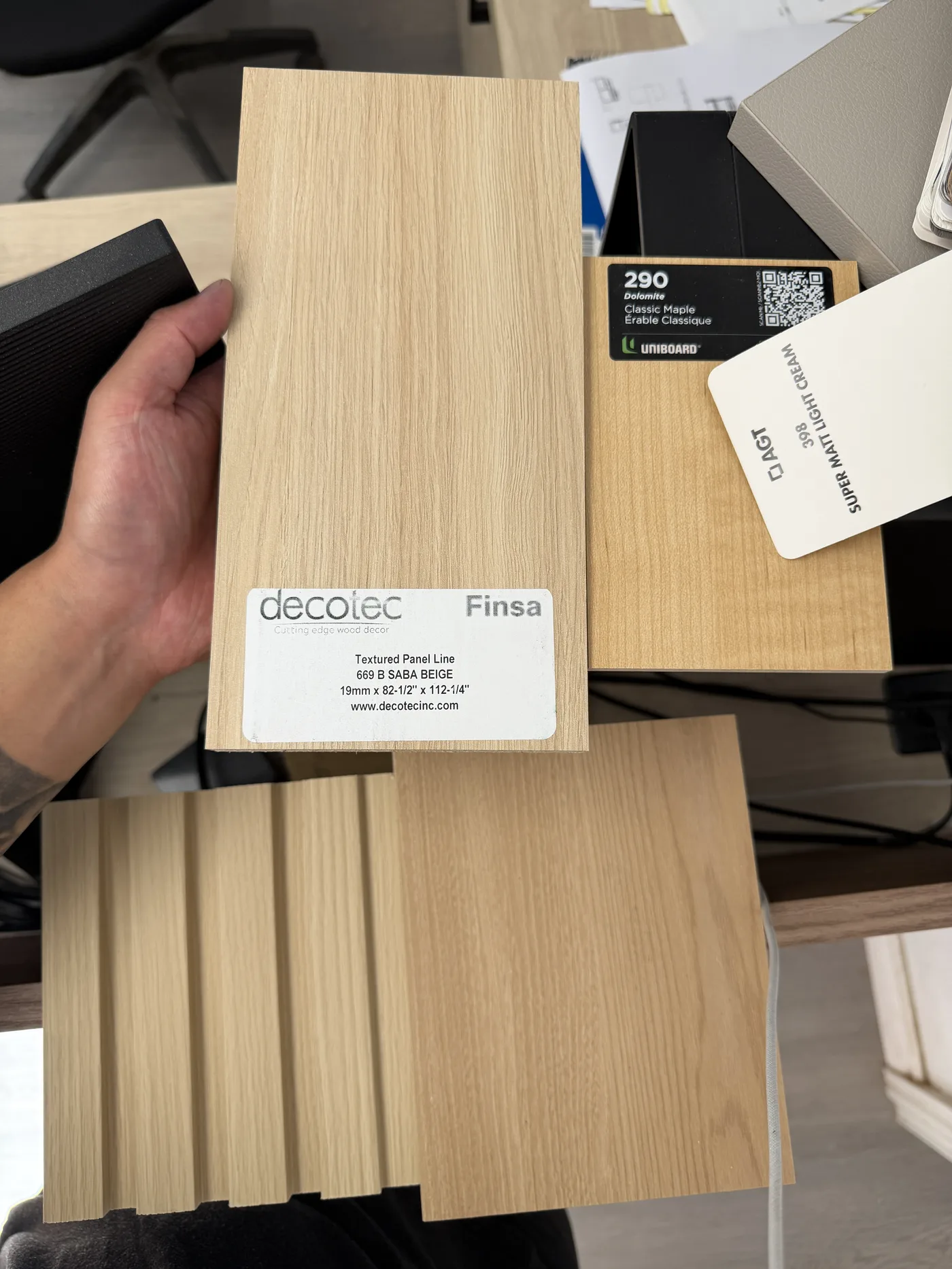 Slatted oak panel samples held up beside a light oak board.