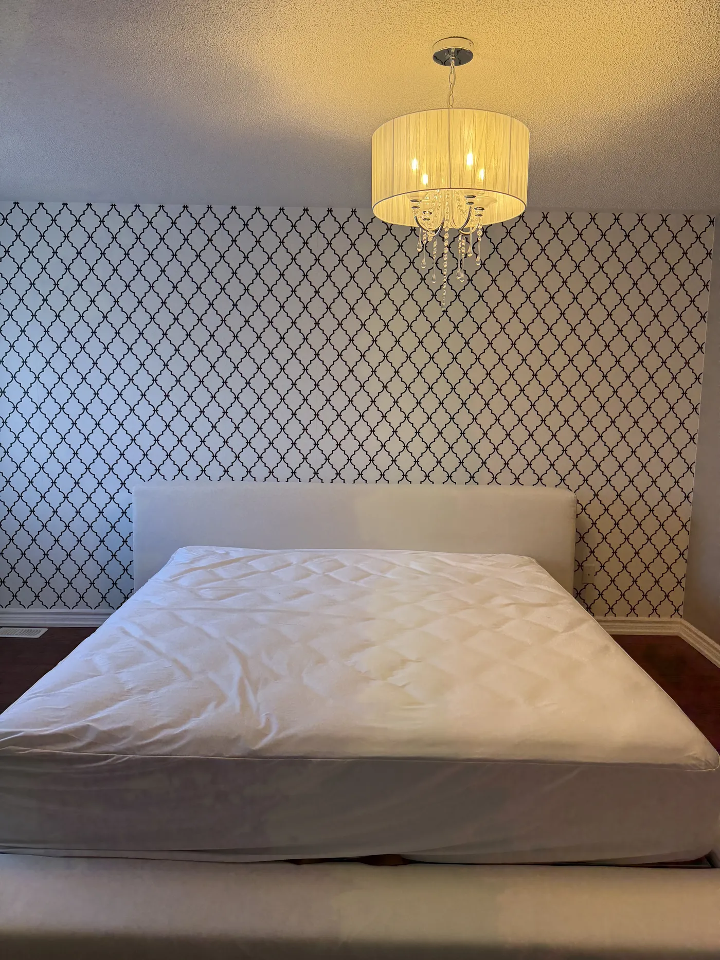 The bedroom before: patterned wallpaper behind the bed.