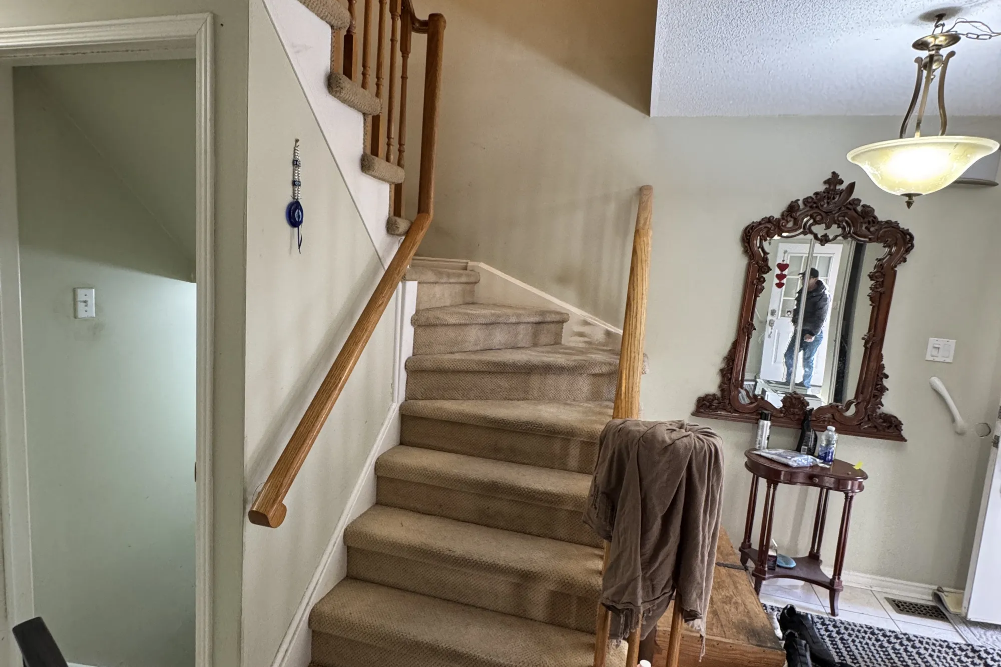 The entry before: a carpeted staircase with an oak banister.