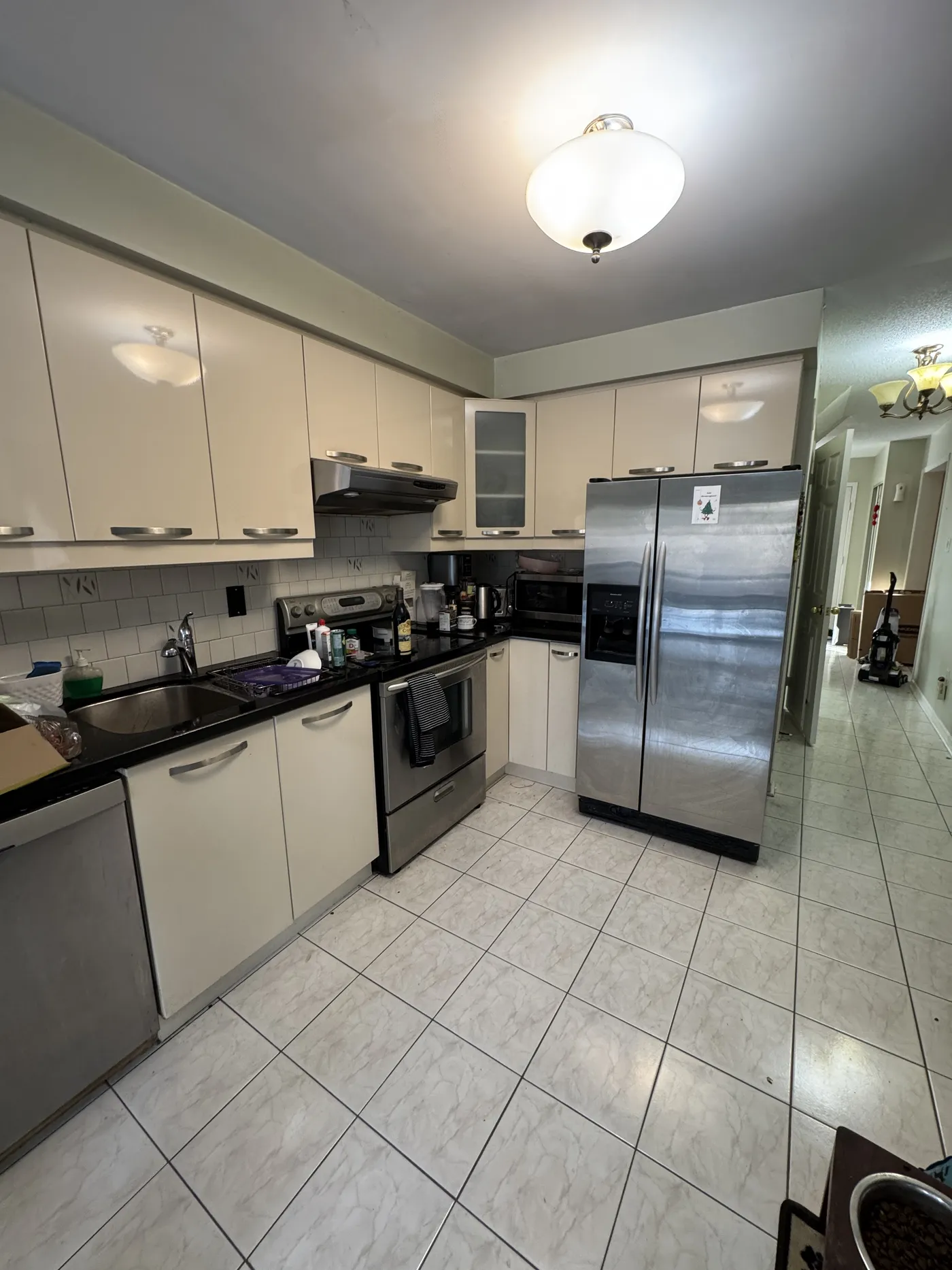 The kitchen before: cream cabinets, black counters and a tiled floor.