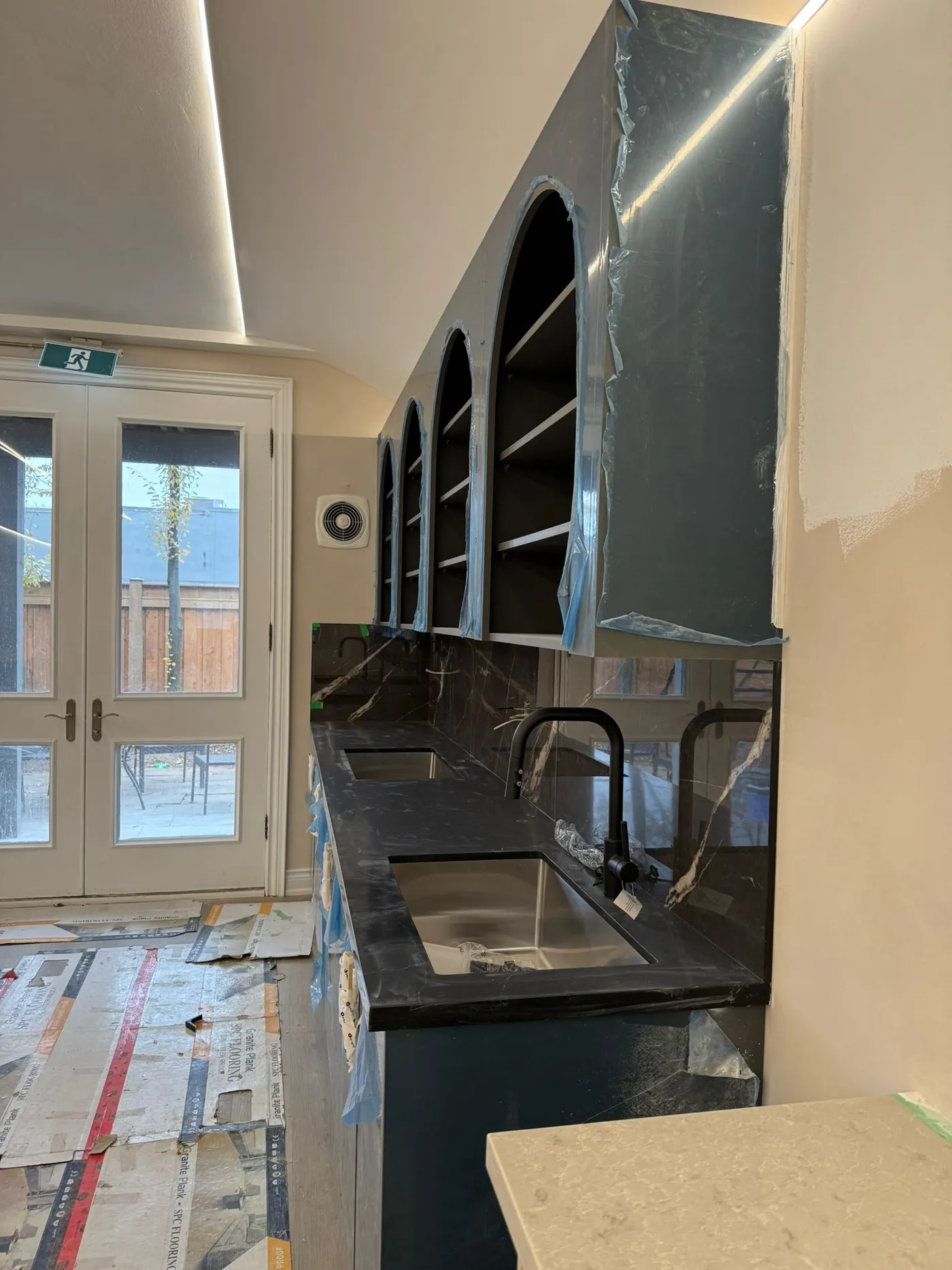 New arched shelving going in above a dark stone counter.