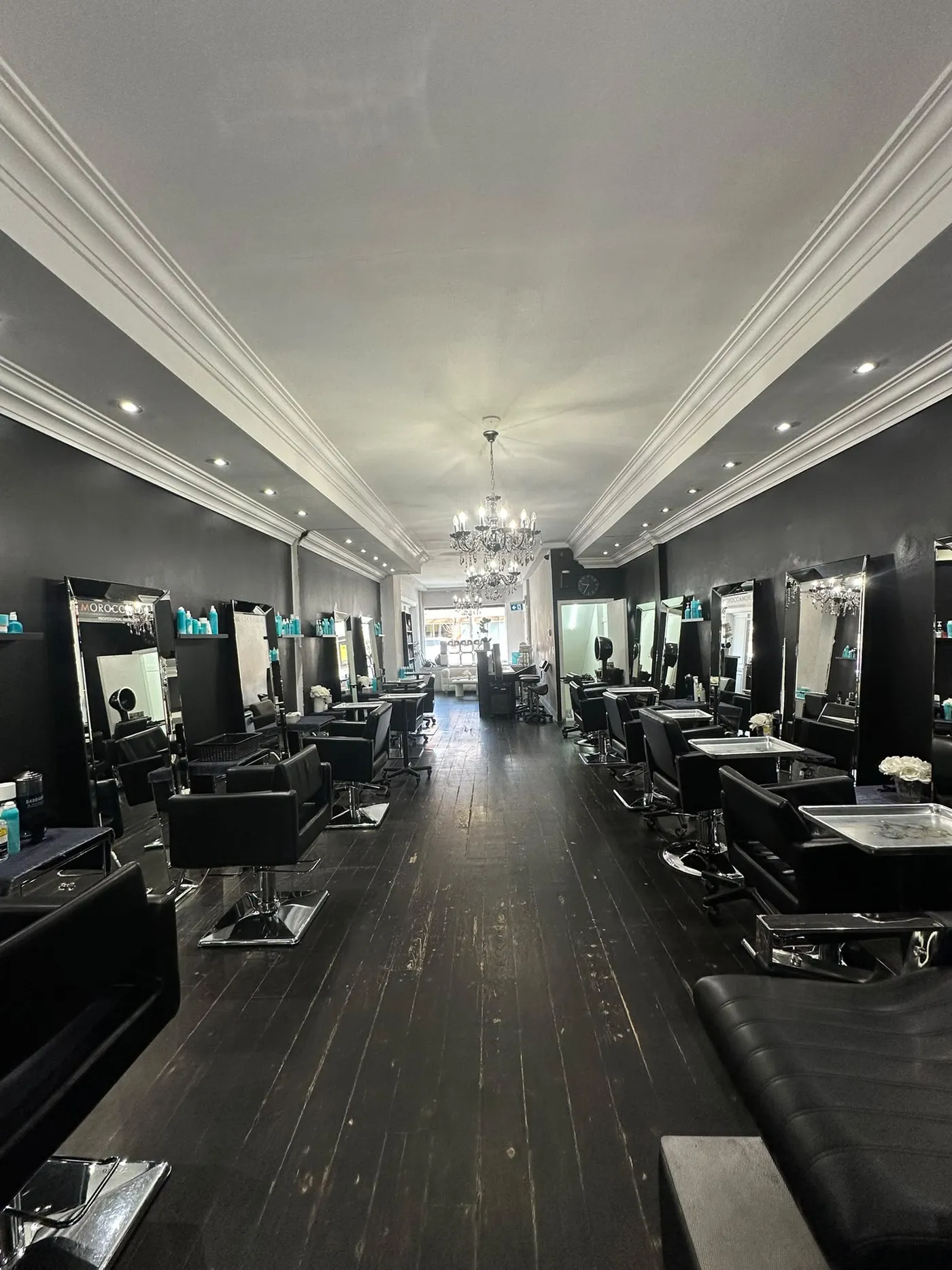 The salon before: black walls, dark floors and a chandelier.