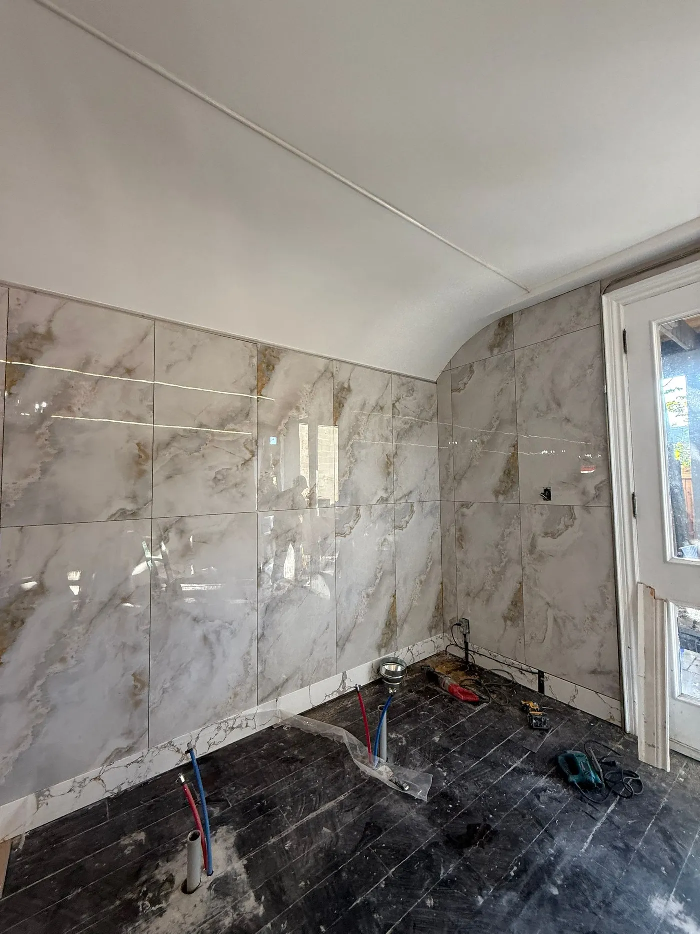 Marble tile going up on the wash station wall.